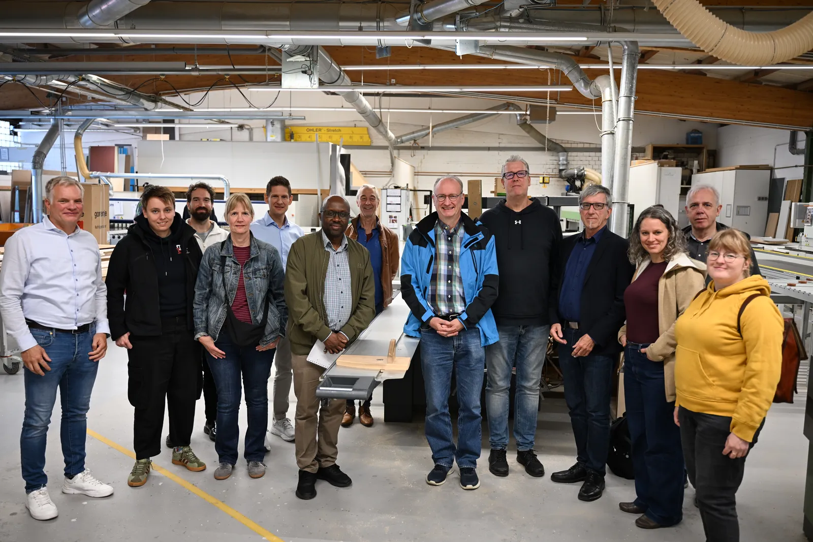 Gruppenfoto: Die Teilnehmerinnen und Teilnehmer des Besuchs stehen nebeneinander in der Werkstatt von Giese & Liebelt.